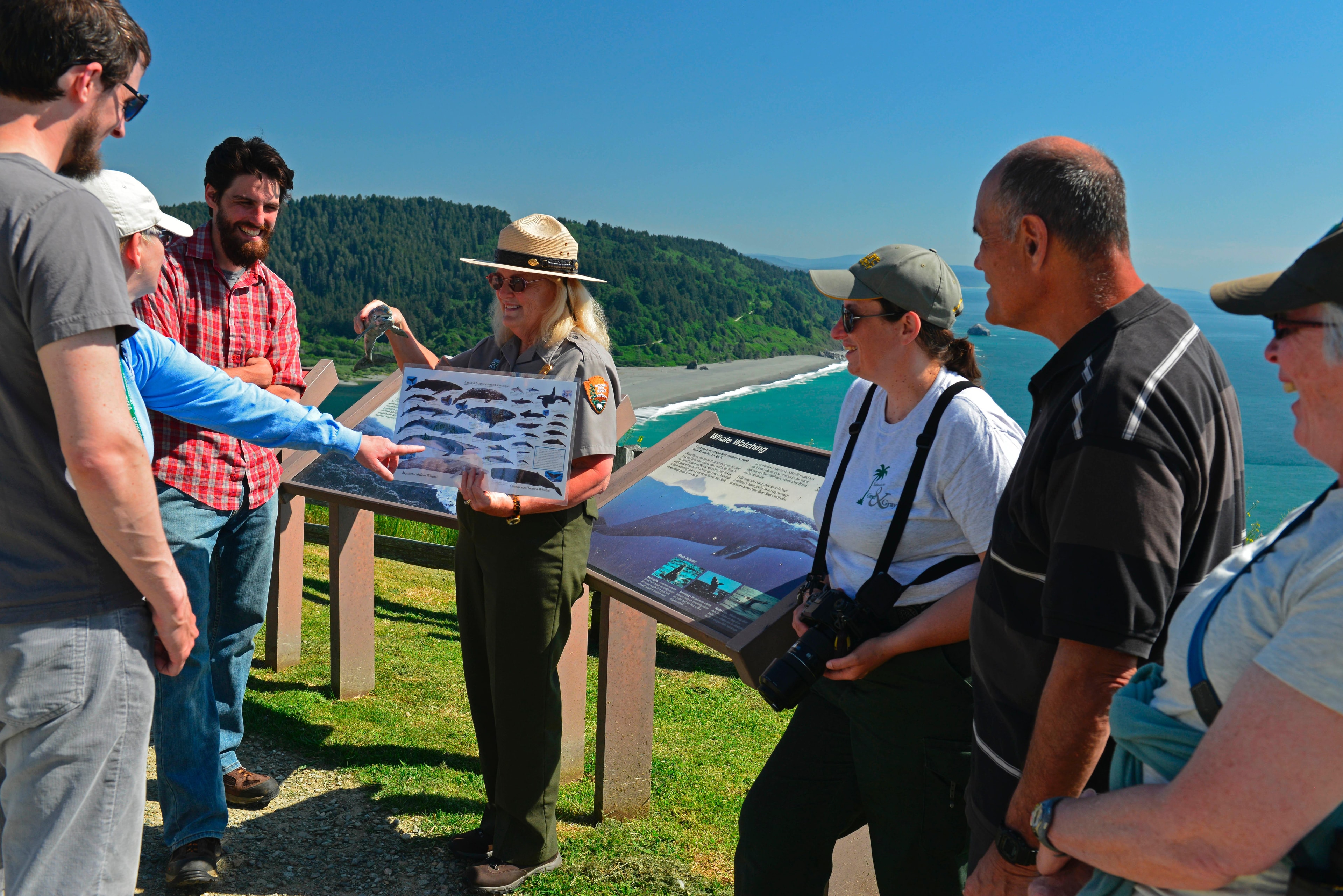 Visitors chatting with a ranger above a river mouth.