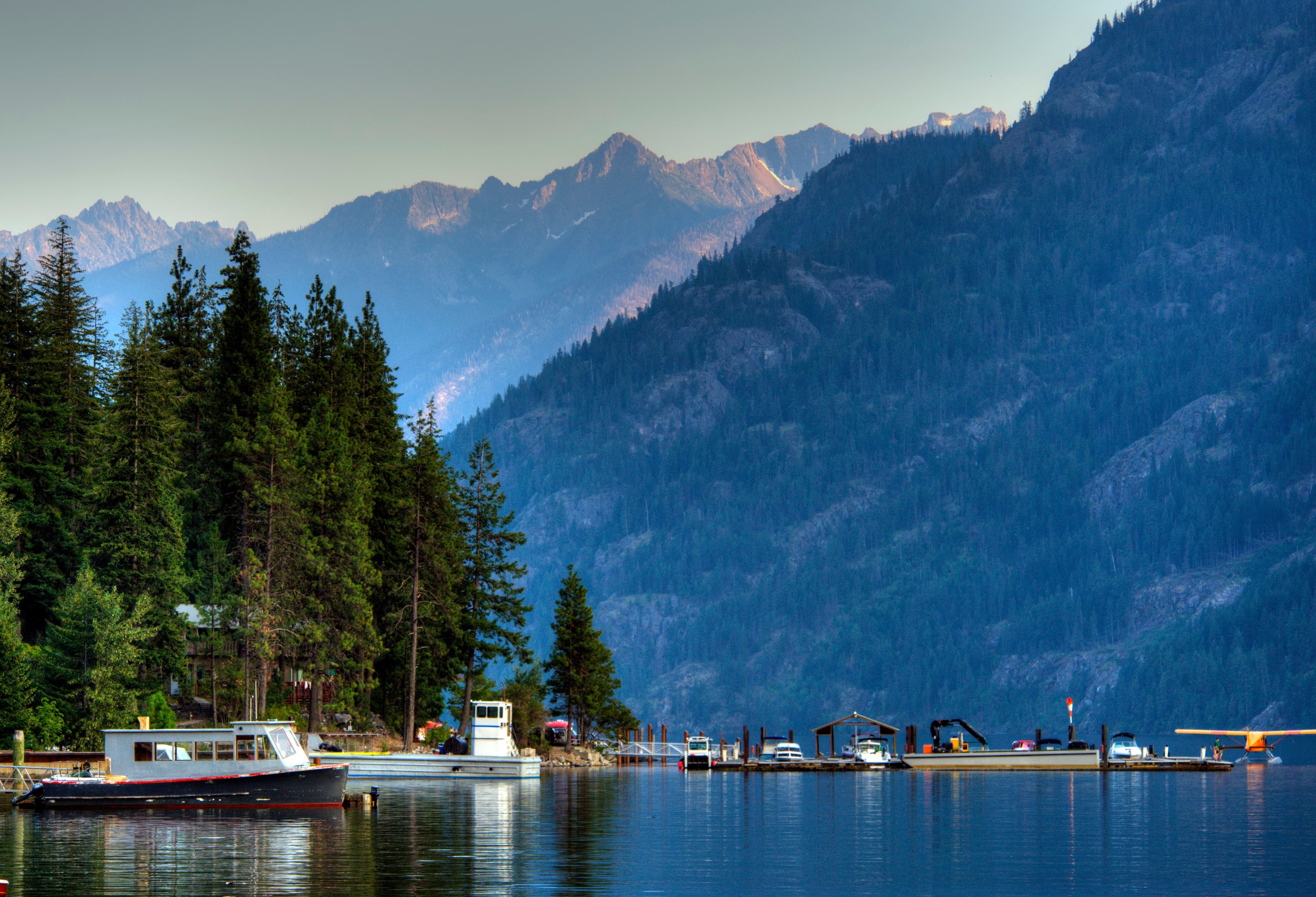 boats on the water with mountains and trees surrounding