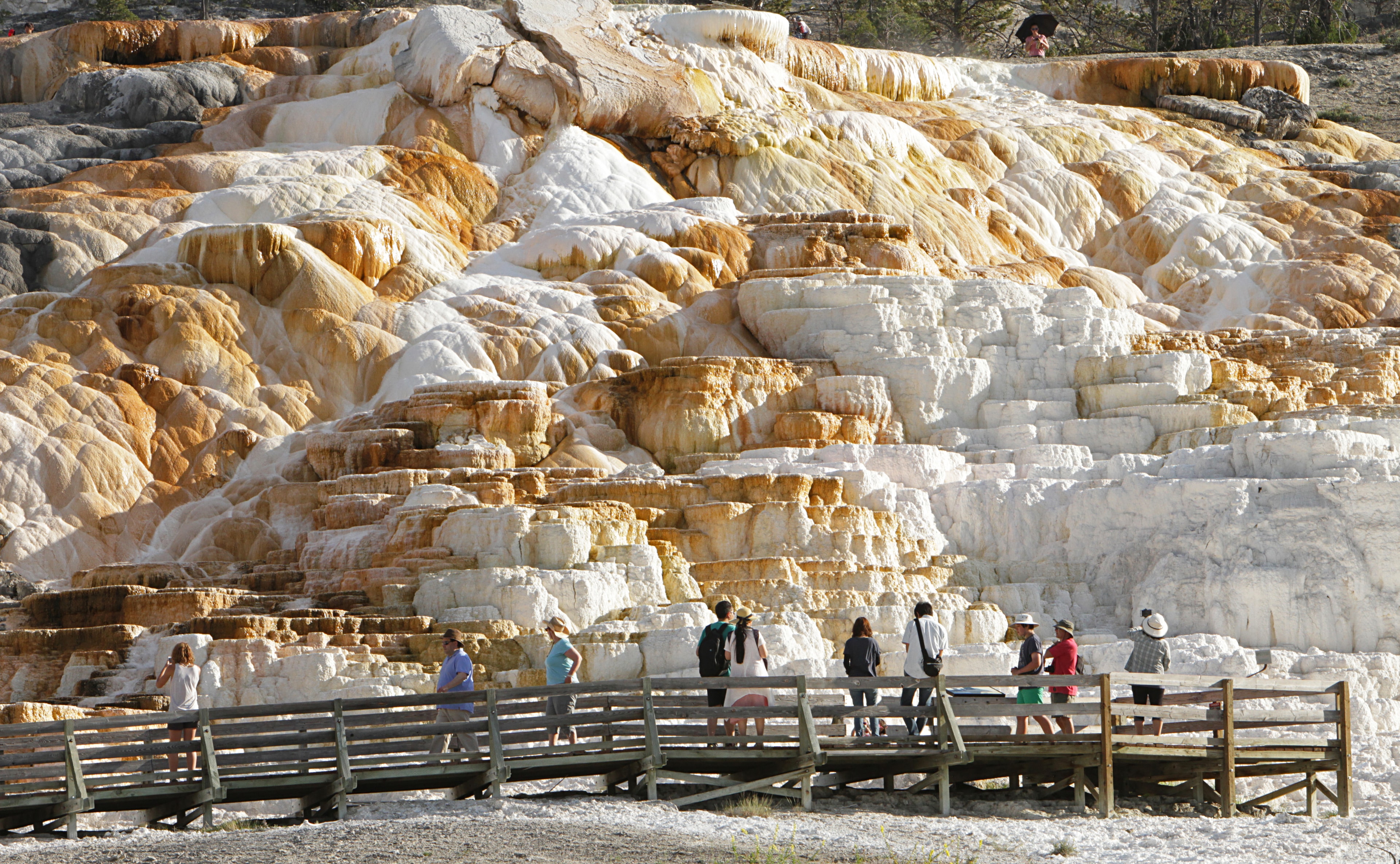 Visitors walk in front of a brightly colored, terraced landscape.