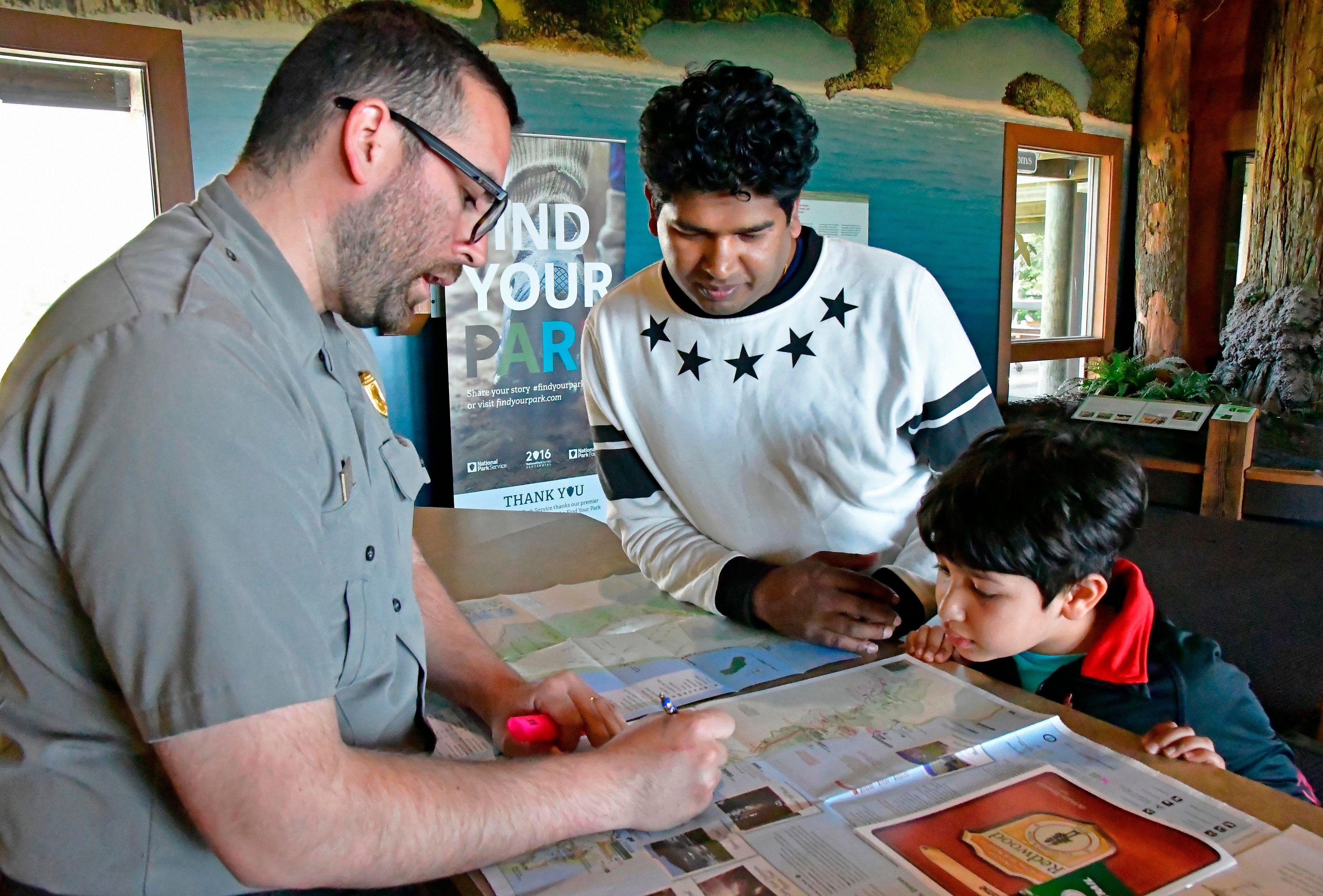 A ranger helps a father and son learn about being a junior ranger.