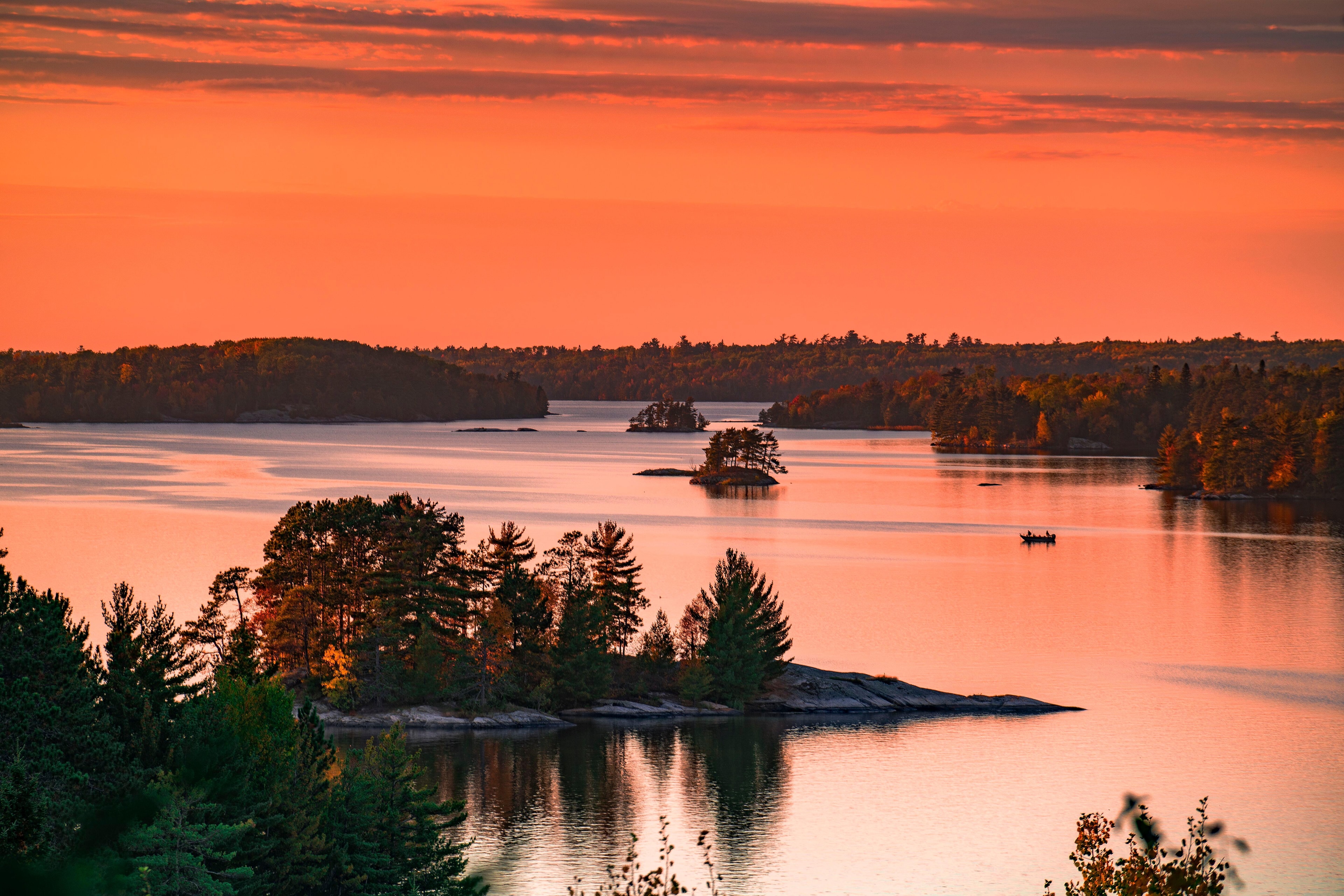 Orange tinted sky with islands scattered throughout the still lake.