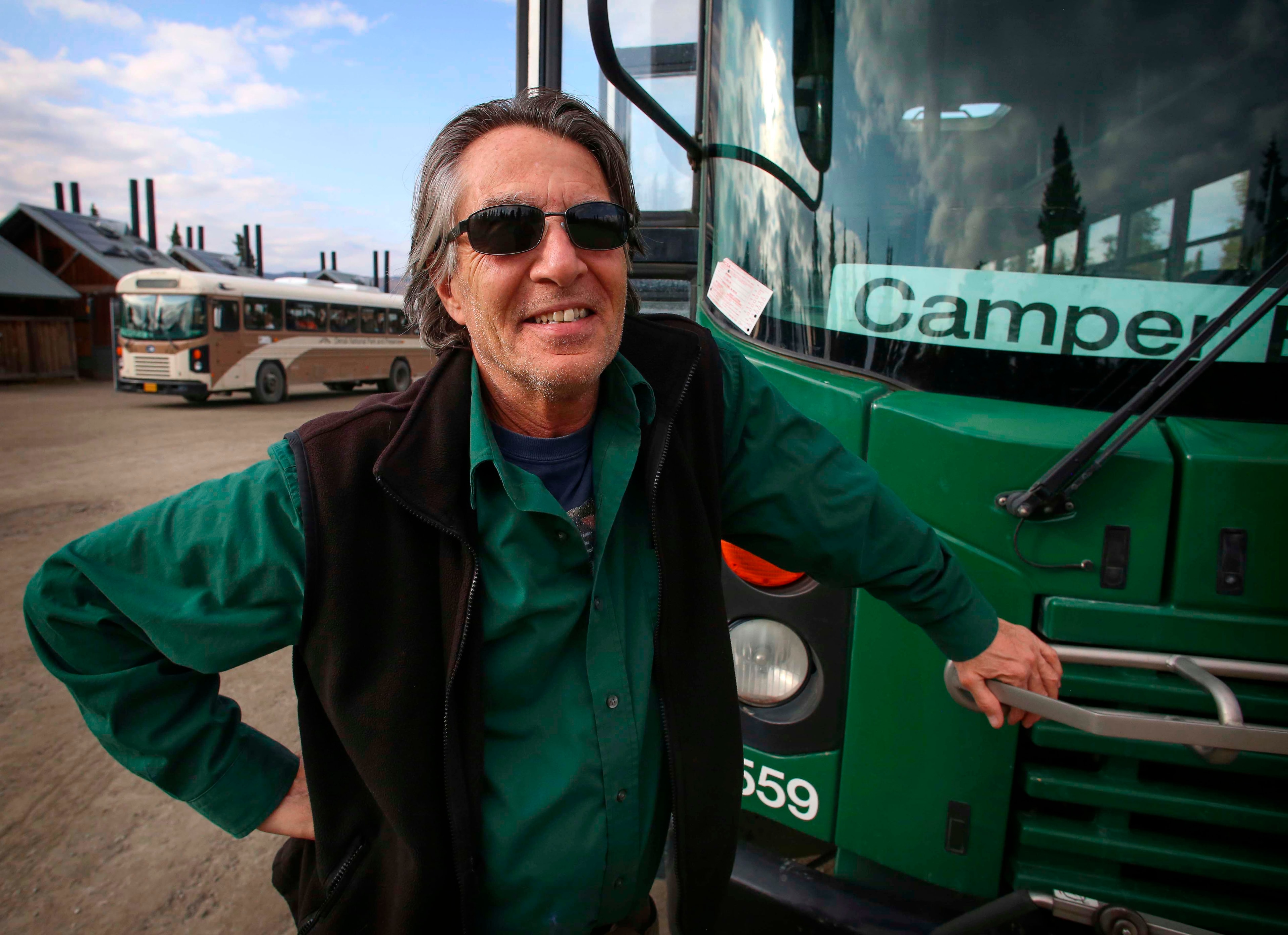 a man standing next to a green bus